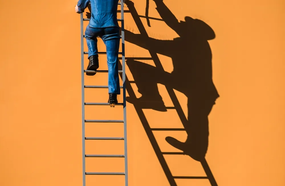 Technician climbing a ladder to inspect and repair sign board construction against a vibrant orange wall